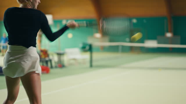 SLO MO Rear View of Sporty Young Female Player in Sportswear Hitting Ball with Racket on Tennis Court in Sports Club