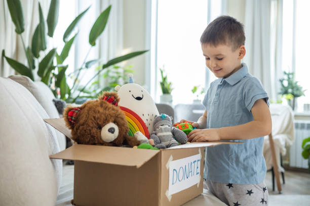un niño pone juguetes en una caja de cartón para caridad. concepto de donación. - box little boys bright car fotografías e imágenes de stock
