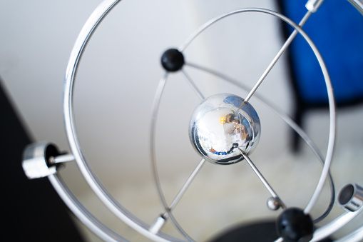 Physics pendulum ball home decoration sphere on blurred background.