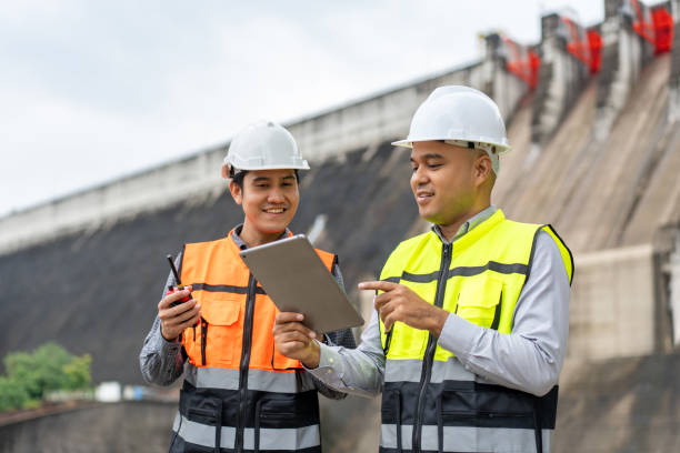 istock Confident asian two maintenance engineers man inspection discussstion with tablet at construction site dam with hydroelectric power plant and irrigation. Team engineer man working at project 1941416412
