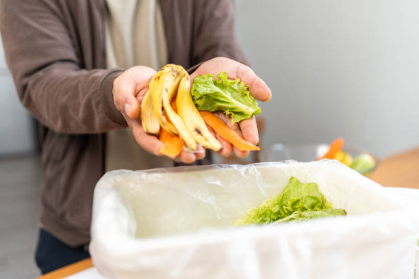 istock Ecology compost supply Kitchen waste recycling composter environmentally friendly. The young man throws leftover fruit peel and vegetables reduce waste 1941426250