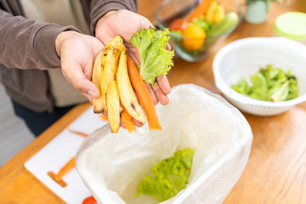 istock Ecology compost supply Kitchen waste recycling composter environmentally friendly. The young man throws leftover fruit peel and vegetables reduce waste 1941426255
