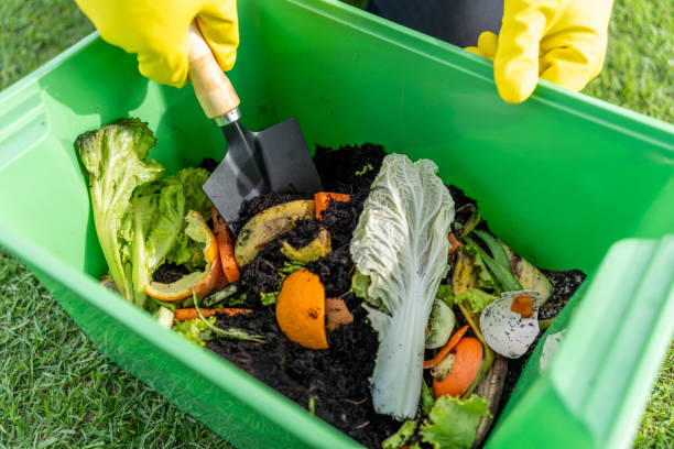istock Ecology compost supply Kitchen waste recycling composter environmentally friendly. The young man throws leftover fruit peel egg shell and vegetables reduce waste 1941427275