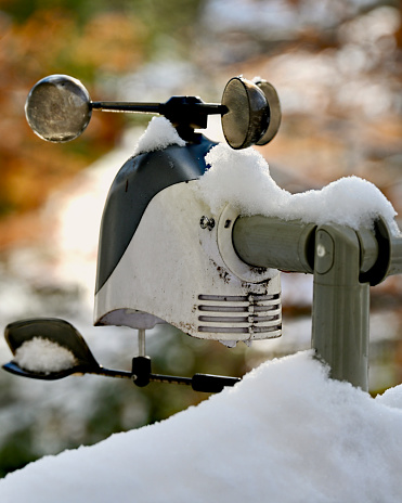 A home weather station covered in snow following an overnight winter storm in a suburban neighborhood.