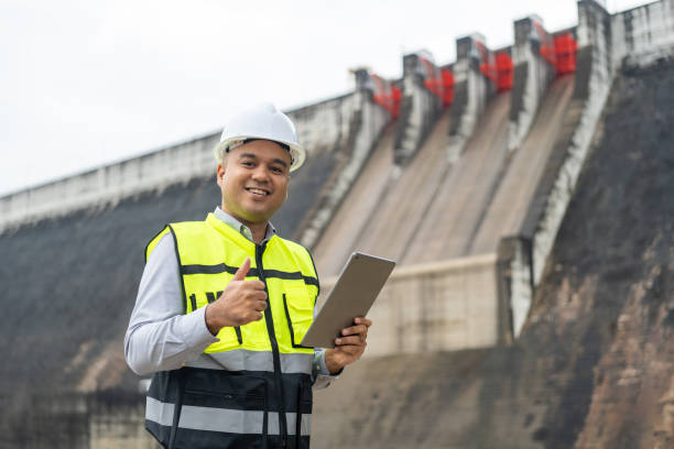 istock Professional asian maintenance engineer man with safety helmet in construction site dam with hydroelectric power plant and irrigation. Manager engineer man working with tablet at project big building. 1941460848