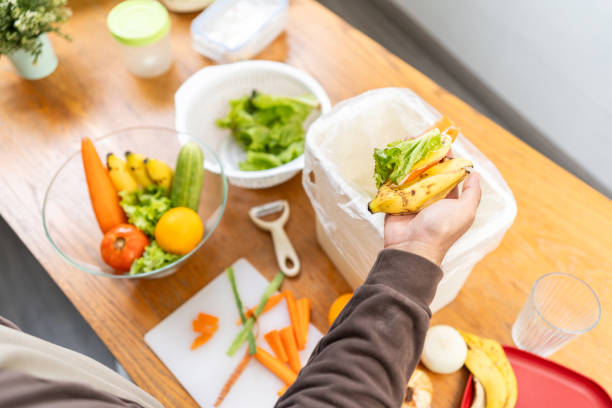istock Ecology compost supply Kitchen waste recycling composter environmentally friendly. The young man throws leftover fruit peel and vegetables reduce waste 1941474945