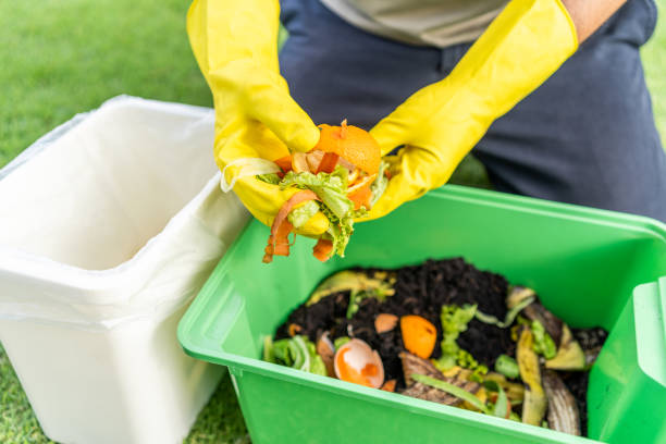 istock Ecology compost supply Kitchen waste recycling composter environmentally friendly. The young man throws leftover fruit peel egg shell and vegetables reduce waste 1941478286
