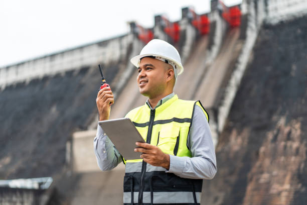 istock Professional asian maintenance engineer man with safety helmet in construction site dam with hydroelectric power plant and irrigation. Manager engineer man working with tablet at project big building. 1941497995