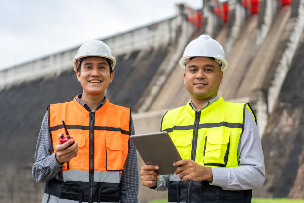 istock Confident asian two maintenance engineers man inspection discussstion with tablet at construction site dam with hydroelectric power plant and irrigation. Team engineer man working at project 1941500072