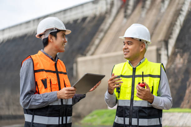 istock Confident asian two maintenance engineers man inspection discussstion with tablet at construction site dam with hydroelectric power plant and irrigation. Team engineer man working at project 1941500076