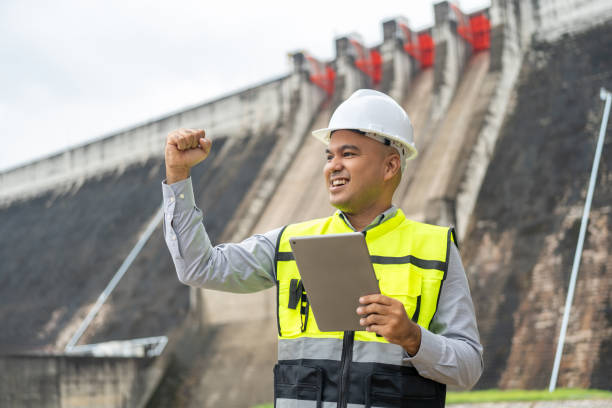 istock Professional asian maintenance engineer man with safety helmet in construction site dam with hydroelectric power plant and irrigation. Manager engineer man working with tablet at project big building. 1941501101