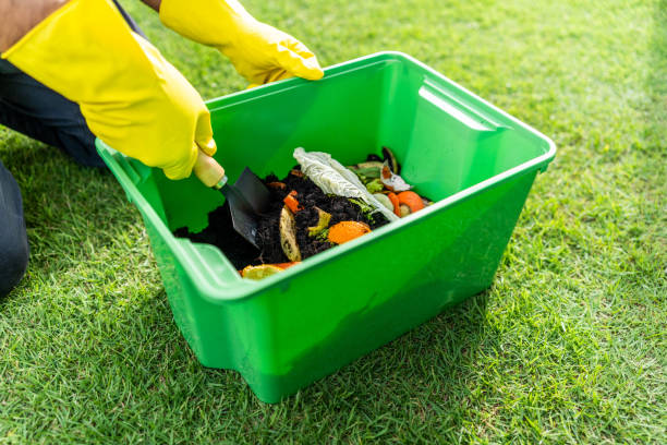 istock Ecology compost supply Kitchen waste recycling composter environmentally friendly. The young man throws leftover fruit peel and vegetables reduce waste 1941506876