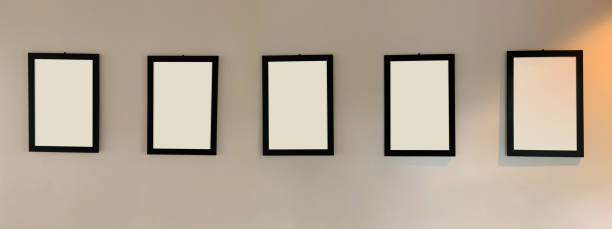 istock Five blank picture frames with black border hanging on the wall with copy space for text 1941513068