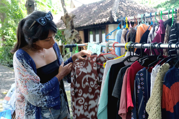 Close-up shot of Conscious Consumer Shopping Clothes in Pop Up Secondhand Store. She's checking out some clothes. concept : Conscious consumerism, ethical marketplace,Green consumer, Eco-friendly consumerism