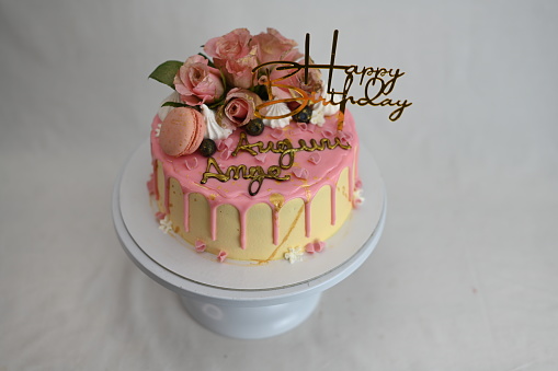 fresh frosted icing dripping pink vanilla birthday cake real roses and macaron decoration on top with golden sign