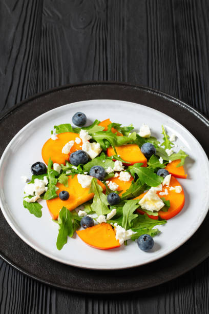 istock arugula persimmon cheese berries salad, top view 1941579130