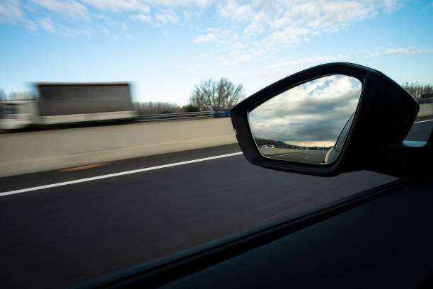 istock Left mirror side view in a sports car riding a highway cloudscape sky 1941627230