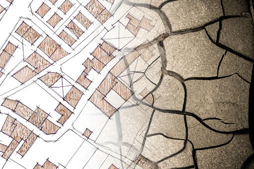 Cracked ground view from above - concept image with an imaginary \ncadastral map of territory with buildings, roads and land parcel