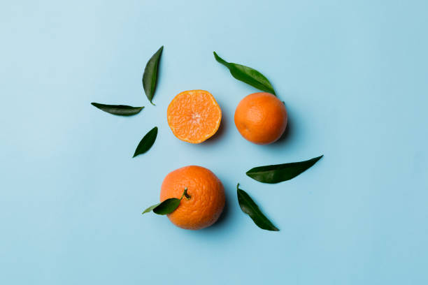 istock Many fresh ripe mandarin with green leaves on colored background, top view, space for text 1941679428