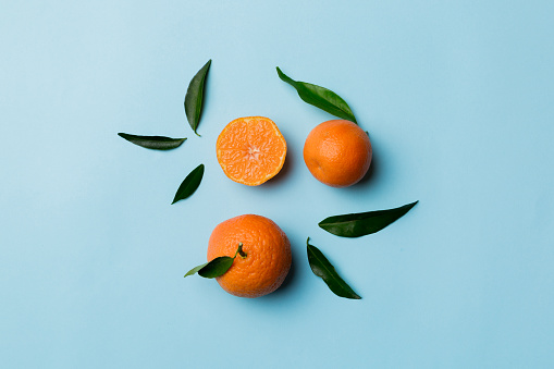 Many fresh ripe mandarin with green leaves on colored background, top view, space for text.