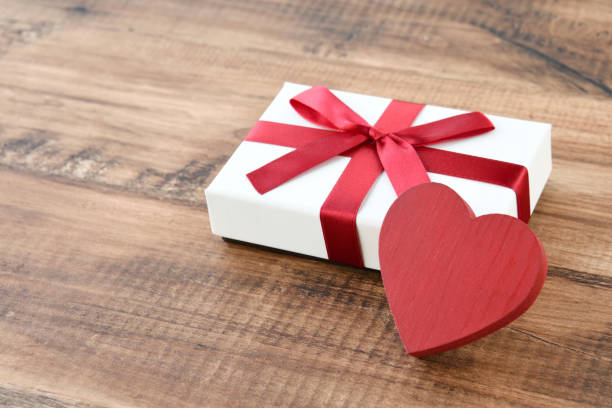istock Heart object and present box on brown wood table 1941687442