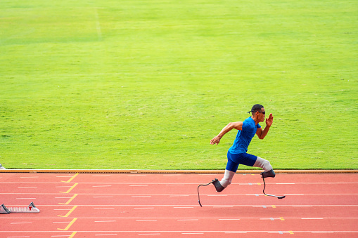 Female fit caucasian runner silhouette in sportswear running fast and jumping through hurdle at dark stadium track