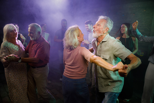 Young at heart senior couples having fun while dancing during nightlife in a disco.