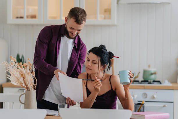 istock Man assisting focused woman with paperwork in a bright home office 1941759376