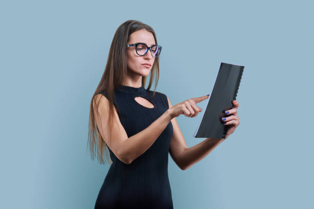 istock Young serious business woman with papers on white studio background 1941760994