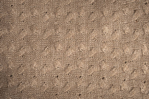 A highly detailed macro image focusing on knitted fabric showcasing colorful textured yarn close-up. The composition features harmonious gradient shades of purple and beige, highlighting soft material craftsmanship and artistic design patterns.