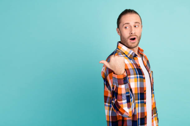 istock Photo of impressed man with stubble dressed checkered shirt indicating staring at offer empty space isolated on teal color background 1941786032