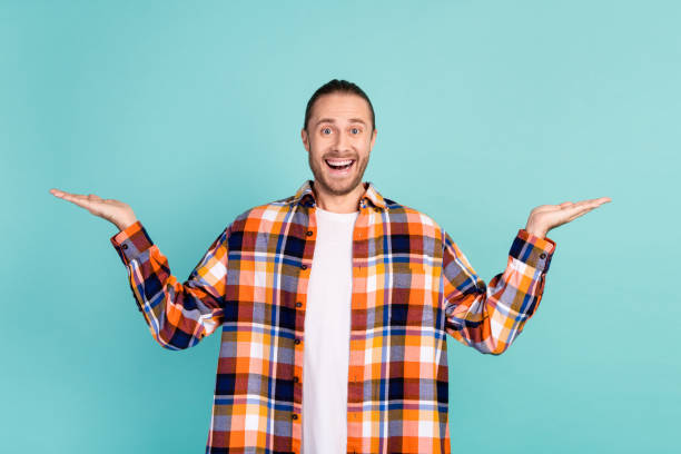 Photo of ecstatic funny man with beard dressed checkered shirt presenting impressive objects empty space isolated on teal color background