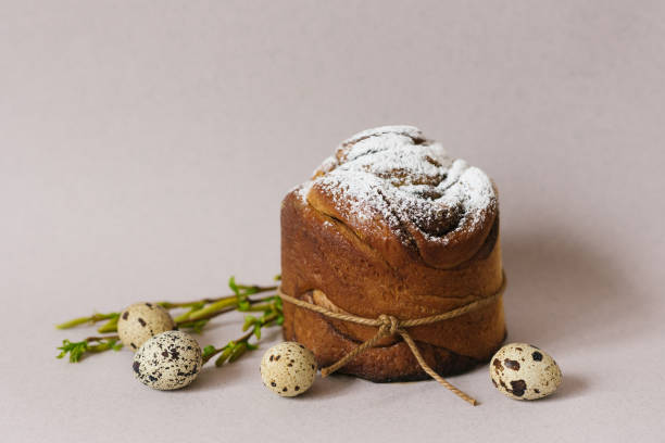 istock Easter holiday card. Sweet cake with powdered sugar and colored chicken eggs on a light beige background with green branches 1941804543