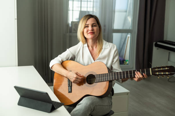 istock Young woman playing her guitar at home 1941825655