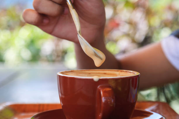 istock Woman's hand holding a spoon and scooping hot coffee cream foam on the table 1941828934