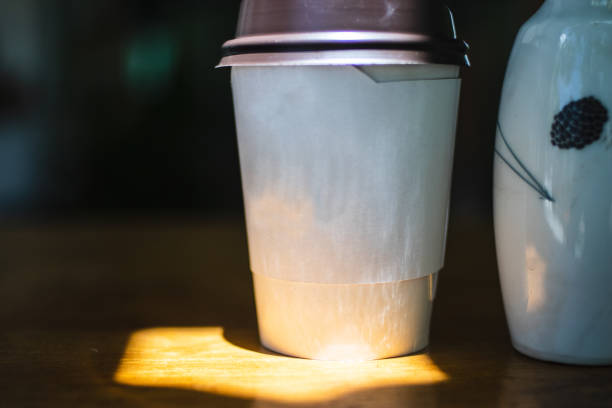 Paper cup of coffee on table with high contrast lighting.
