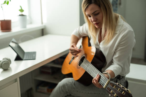 istock Young woman playing her guitar at home 1941833919
