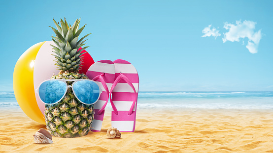 Funny pineapple with sunglasses sunbathing at the beach, summer vacations concept, copy space