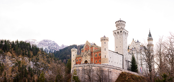 Fussen, Germany - August 7, 2015: Beautiful view of world-famous Neuschwanstein Castle, the nineteenth-century Romanesque Revival palace built for King Ludwig II on a rugged cliff, with scenic mountain landscape near Fussen, southwest Bavaria, Germany.