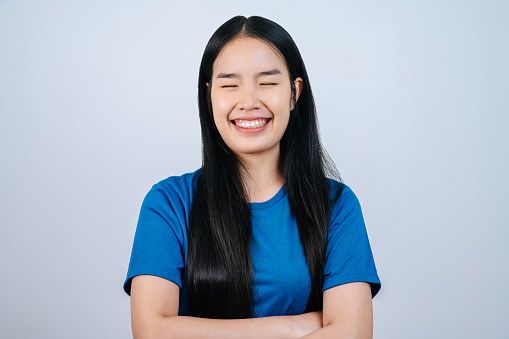 Portrait of Young Asian woman straight long hair with close eye and arms crossed on white background in studio,Hair styling