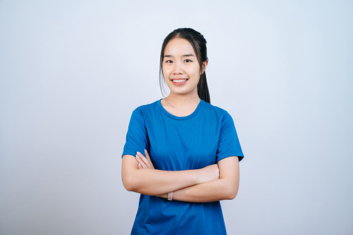 Portrait of Young Asian woman with long ponytail and arms crossed on white background in studio, hair styling