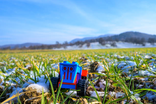 Symbolic Agriculture: Mini Tractor Toy Navigates Snow-Covered German Agrarian Meadow
