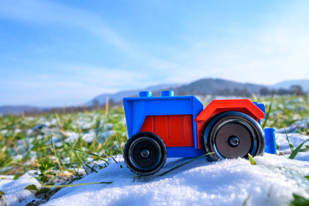 Plastic toy tractor red and blue in agriculture on snowy field in Germany