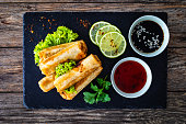 Spring rolls filled with meat and vegetables served with soy sauce on wooden table