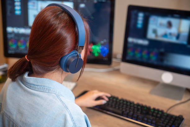 istock Female asian freelancer editing video for customer or travel blogger in program on computer while sitting at the table and working at home 1941914569