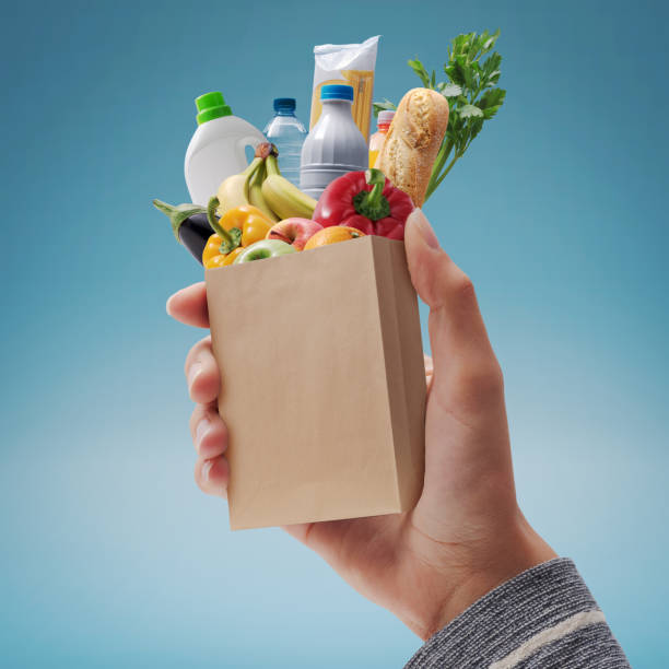 istock Customer holding a miniature grocery bag with assorted goods 1941927536