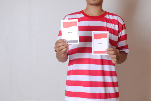 Voting papers for general elections or Pemilu for the president and government of Indonesia. Cropped portrait of asian man holding ballot. stock photo