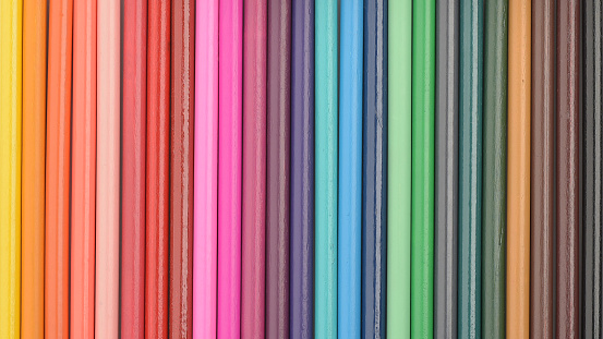 Coloured pencils bodies arranged in a row. Wooden texture. Colour spectrum sharp background.