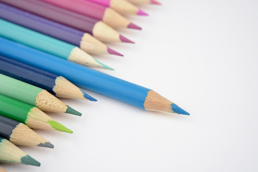 Concept of choice or Leadership with coloured pencils A focus on blue pencil Close up White background