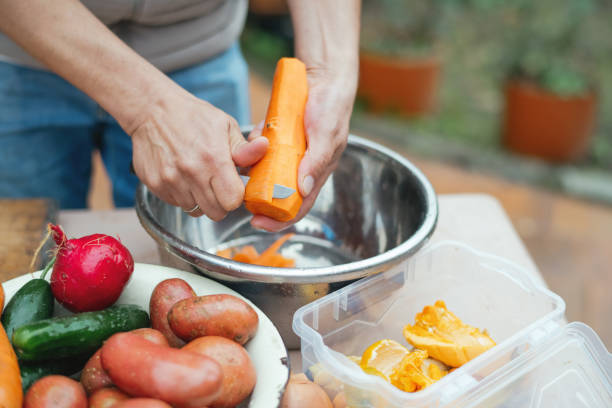 istock Close up of a man peeling vegetables and making compost from leftovers at an open kitchen outdoors at back yard. Sustainable lifestyle and zero waste cooking concept. 1941945512